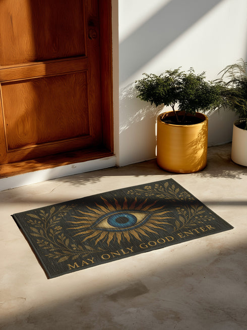 Woven doormat with non-slip backing, featuring a blue evil eye at center surrounded by golden botanical rays and the phrase "May Only Good Enter" along the edge, made of soft 100% polyester chenille with a smooth plush pile, 24x36 inches in size, designed for witchy or spiritual home décor and entry protection.
